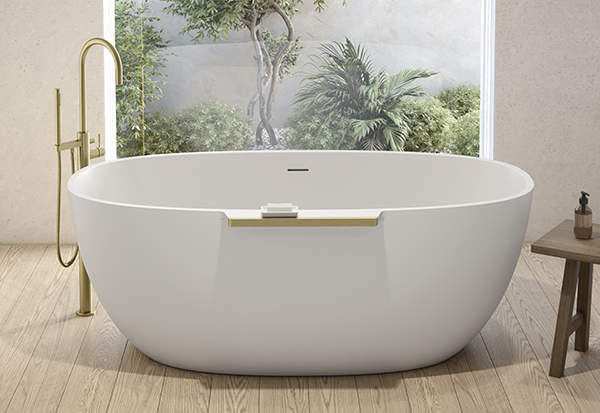 An oval white freestanding bathtub with a floor-mounted faucet in brushed gold